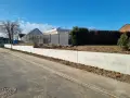 La **fondation mur de soutènement** en béton est prête pour le jardinage. Le ciel bleu et les maisons en arrière-plan annoncent le printemps.