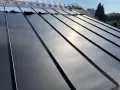 Pose de feuilles de toit en zinc sur une nouvelle construction. Le soleil brille sur le métal lisse.