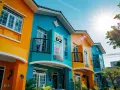 Maisons colorées D2 et D3 sous un soleil éclatant. La peinture vive des façades orange et bleu turquoise attire le regard.