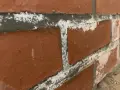 Efflorescence blanche sur les joints d'un mur de briques, signe de salpêtre dans la maison.