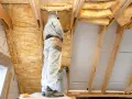 Pose de **panneau isolant toiture** dans un grenier par des ouvriers en combinaison.