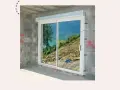 Fenêtre coulissante en PVC installée dans un mur en parpaings, offrant une vue sur un paysage montagneux. Idéal pour apprendre comment poser une fenêtre de toit.