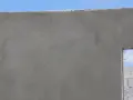 Le ragréage du mur extérieur est presque terminé, offrant une surface lisse et uniforme avant l'application de la finition.