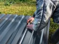 Un ouvrier mesure une tôle de bac acier pour un toit plat.