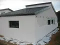 Maison en construction avec murs en **béton cellulaire extérieur**. Fenêtres noires et toit sombre.