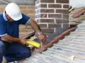 Un couvreur installe un solin en plomb pour l'étanchéité de cheminée, assurant une protection durable contre les intempéries.