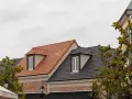 Toits de bâtiments avec différents types de tuiles : une toiture en tuiles d'argile orangées et une autre en tuiles d'ardoise grises.