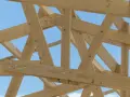 Assemblage ferme charpente en bois, structure solide sous un ciel bleu.