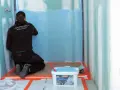 Un ouvrier applique un système d'étanchéité liquide bleu sur les murs d'une douche. Un seau de produit est visible au premier plan.