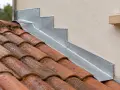 Détail d'une pose de solin en zinc contre un mur, protégeant les tuiles de la pluie.