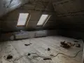 Grenier en cours d'aménagement, avec pare-vapeur fibre de bois, deux fenêtres de toit et un plancher en bois brut. Outils de bricolage au sol.