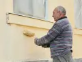 Un homme peint une façade jaune avec un rouleau.