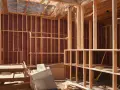 Intérieur d'une maison en construction, avec charpente en bois et pose de laine de verre sur les murs.
