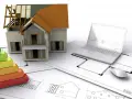 Maquette de maison, échelle d'énergie, plans et ordinateur portable. L'isolation RGE Qualibat est essentielle pour une maison performante.