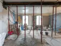 Chantiers : étais métalliques soutenant une poutre en cours de consolidation pour le prix d'une fondation maison. Matériaux et outils de construction visibles.