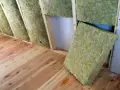 Isolation d'un grenier avec de la laine de verre sans pare vapeur, posée sur un plancher en bois brut.