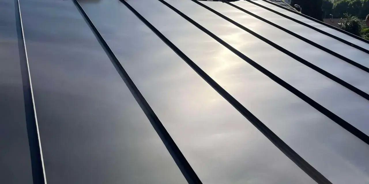 Pose de feuilles de toit en zinc sur une nouvelle construction. Le soleil brille sur le métal lisse.