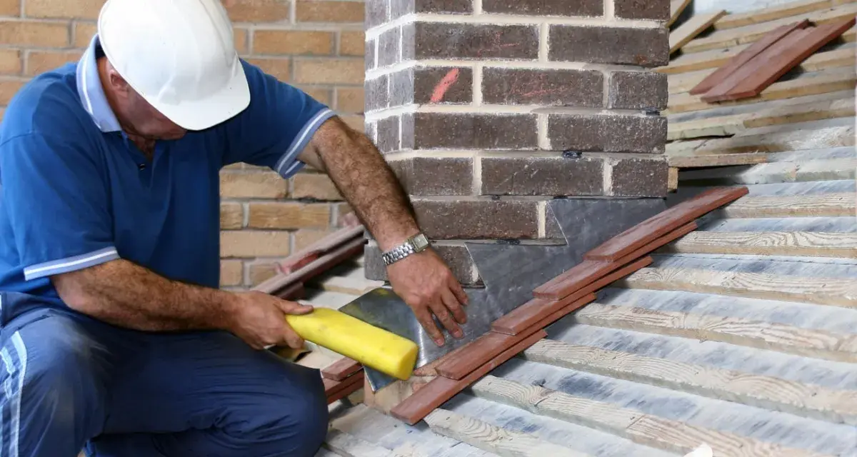 Un couvreur installe un solin en plomb pour l'étanchéité de cheminée, assurant une protection durable contre les intempéries.