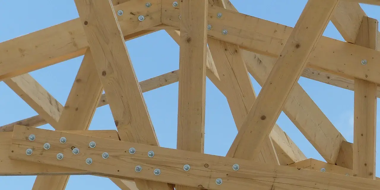 Assemblage ferme charpente en bois, structure solide sous un ciel bleu.