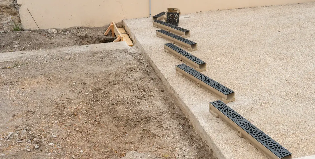 Installation de plusieurs éléments de pose caniveau sur un chantier.
