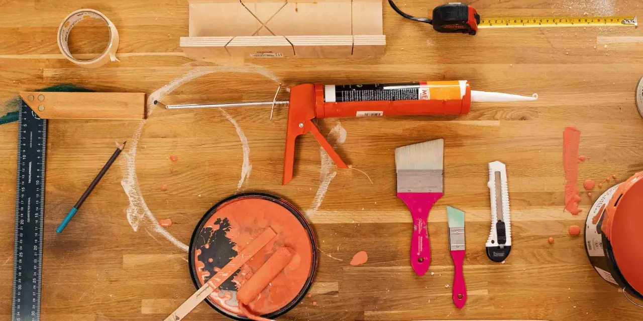 Pistolet à mastic acrylique, rouleau, pinceaux, ruban adhésif, mètre et boîte à onglets pour une utilisation en bricolage.