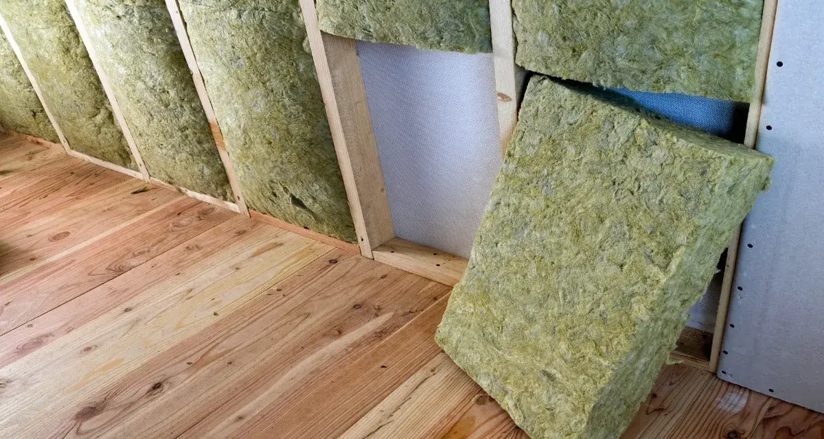 Isolation d'un grenier avec de la laine de verre sans pare vapeur, posée sur un plancher en bois brut.