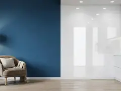 Un fauteuil confortable près d'un mur bleu mat, contrastant avec une cuisine blanche aux surfaces brillantes.
