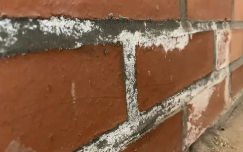 Efflorescence blanche sur les joints d'un mur de briques, signe de salpêtre dans la maison.
