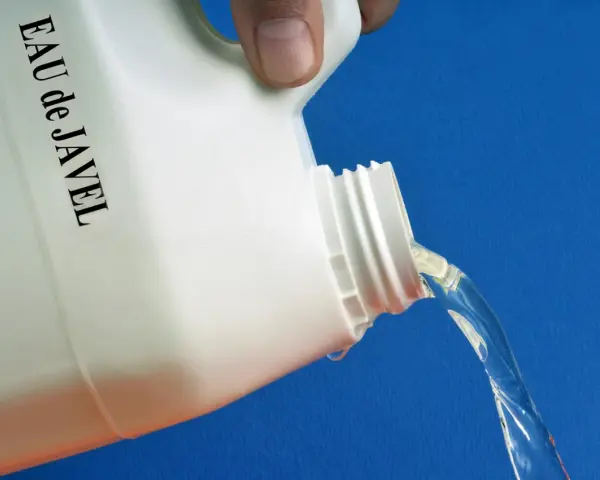 Maintenant, quelle dilution eau de javel pour nettoyer façade ? Un bidon blanc étiqueté "EAU de JAVEL" verse un liquide clair sur fond bleu.