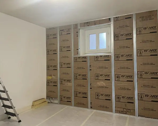 Pose de laine de verre ISOVER en 2 couches sur une structure métallique, avec une fenêtre au centre.