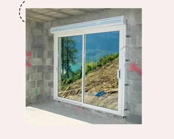 Fenêtre coulissante en PVC installée dans un mur en parpaings, offrant une vue sur un paysage montagneux. Idéal pour apprendre comment poser une fenêtre de toit.