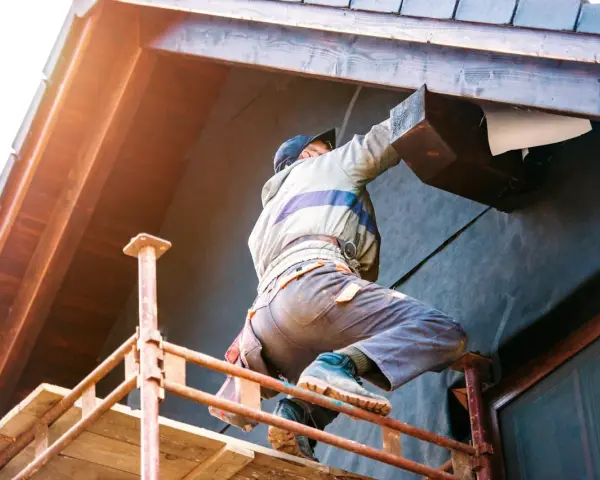 Un ouvrier sur échafaudage réalise l'isolation extérieure d'une maison. Une entreprise RGE pour des travaux d'isolation extérieure performants.