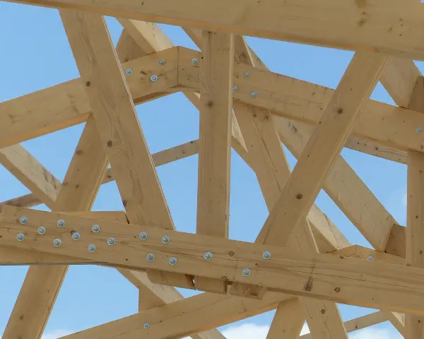 Assemblage ferme charpente en bois, structure solide sous un ciel bleu.