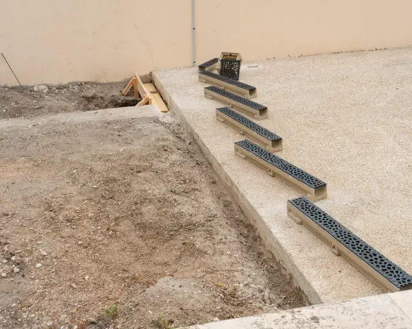 Installation de plusieurs éléments de pose caniveau sur un chantier.