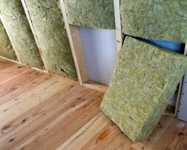 Isolation d'un grenier avec de la laine de verre sans pare vapeur, posée sur un plancher en bois brut.