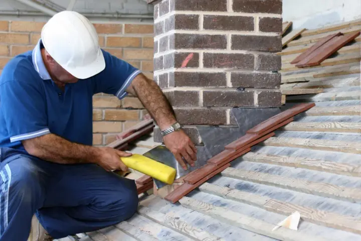 Un couvreur installe un solin en plomb pour l'étanchéité de cheminée, assurant une protection durable contre les intempéries.