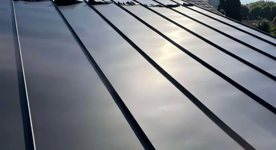 Pose de feuilles de toit en zinc sur une nouvelle construction. Le soleil brille sur le métal lisse.