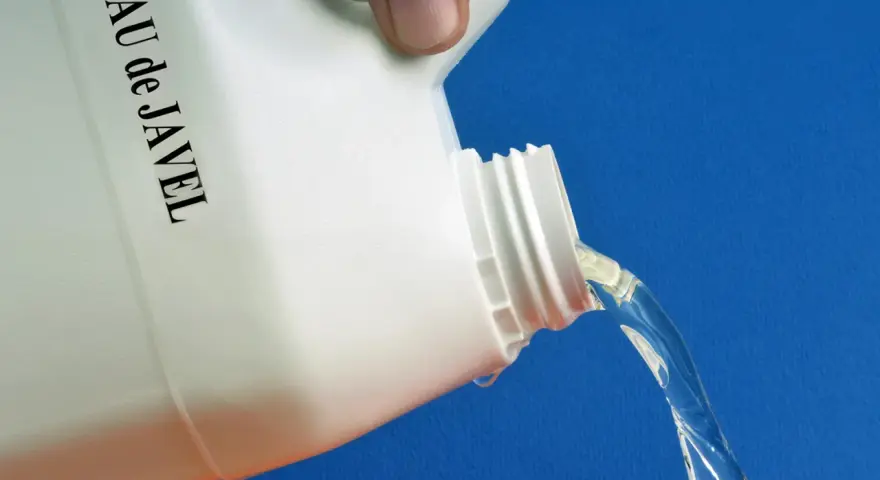 Maintenant, quelle dilution eau de javel pour nettoyer façade ? Un bidon blanc étiqueté "EAU de JAVEL" verse un liquide clair sur fond bleu.