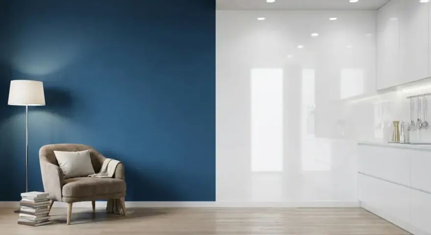 Un fauteuil confortable près d'un mur bleu mat, contrastant avec une cuisine blanche aux surfaces brillantes.