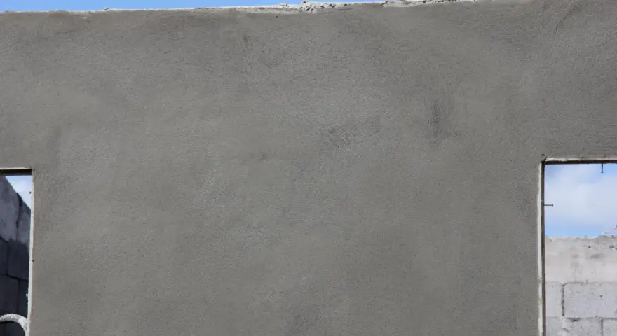 Le ragréage du mur extérieur est presque terminé, offrant une surface lisse et uniforme avant l'application de la finition.