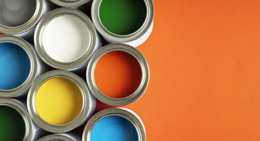 Un assortiment de pots de peinture glycero ou acrylique ouverts, révélant des couleurs vives comme le bleu, le jaune, le rouge, le vert et l'orange sur fond orange.