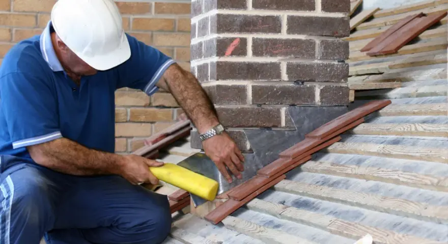 Un couvreur installe un solin en plomb pour l'étanchéité de cheminée, assurant une protection durable contre les intempéries.