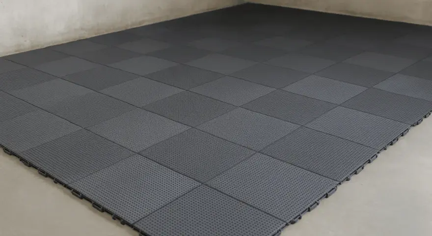 Dalles modulaires grises posées sur un sol de garage. L'épaisseur de la dalle béton garage est ici optimisée par ce revêtement pratique.