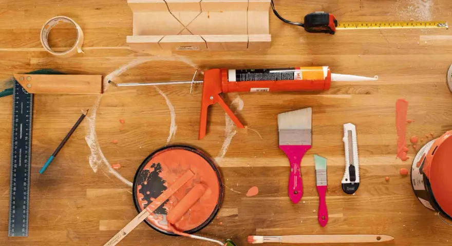 Pistolet à mastic acrylique, rouleau, pinceaux, ruban adhésif, mètre et boîte à onglets pour une utilisation en bricolage.
