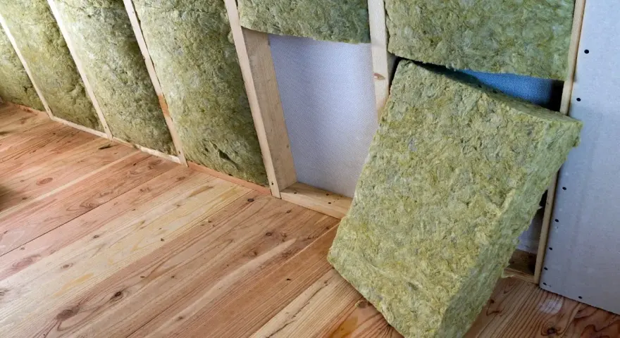 Isolation d'un grenier avec de la laine de verre sans pare vapeur, posée sur un plancher en bois brut.