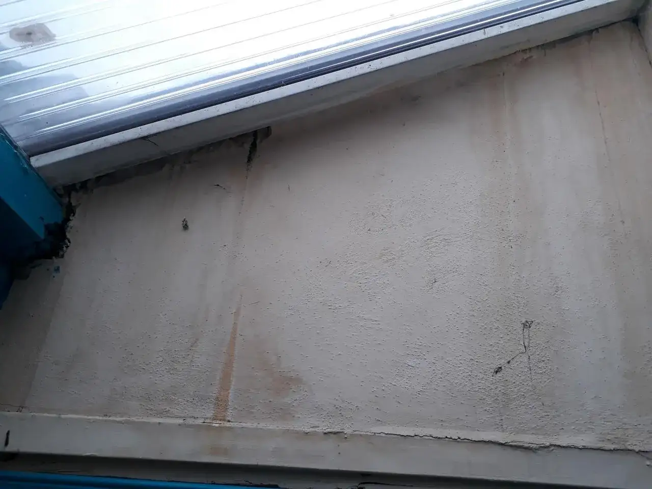 Traces d'humidit&eacute; sur le mur d'une v&eacute;randa, indiquant un probl&egrave;me d'&eacute;tanch&eacute;it&eacute; &agrave; r&eacute;soudre.