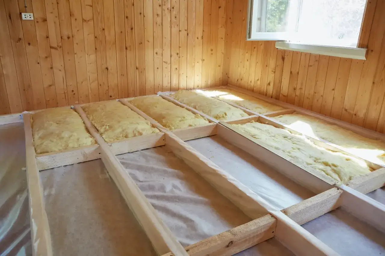 Isolation de plancher bois : solives en bois avec isolant jaune posé, sous une fenêtre.