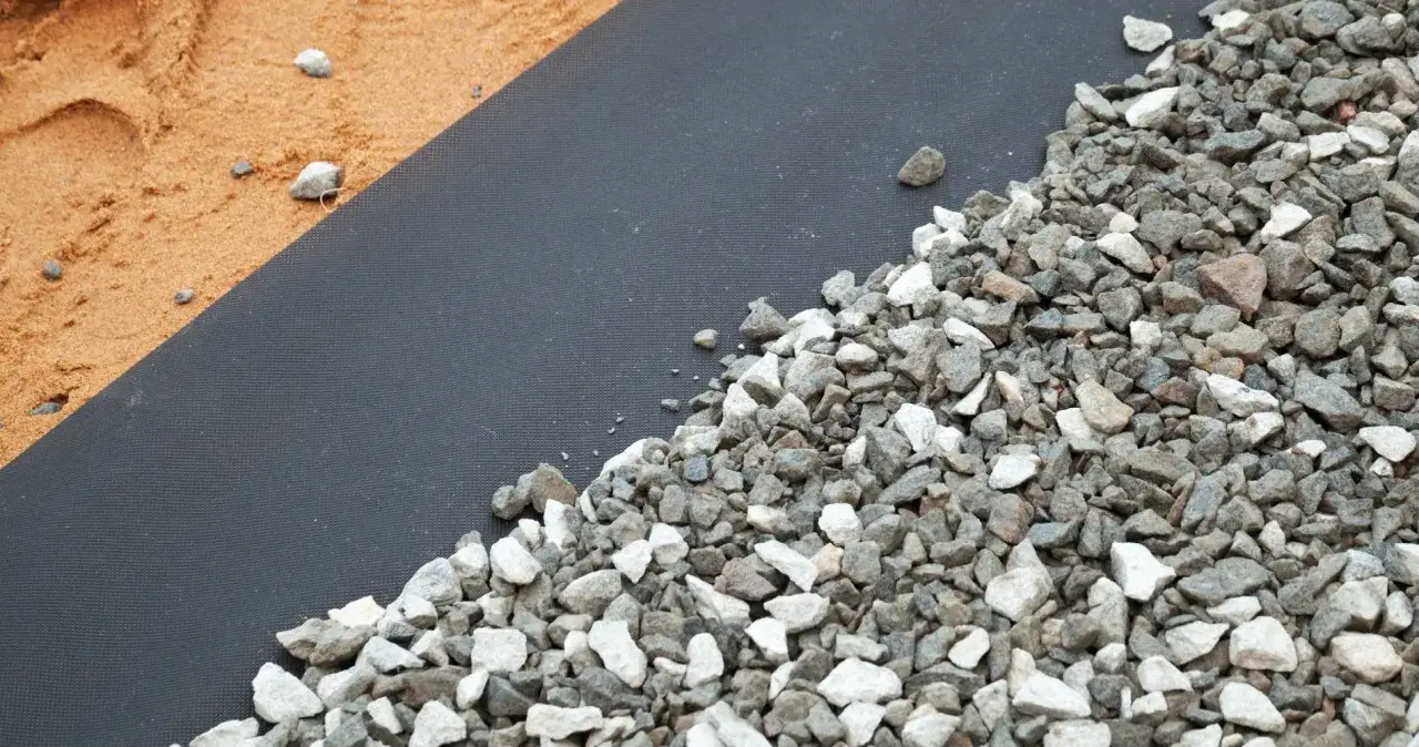 Gravel et sable sur un g&eacute;otextile noir. Aide &agrave; choisir quel geotextile choisir pour vos projets ext&eacute;rieurs.