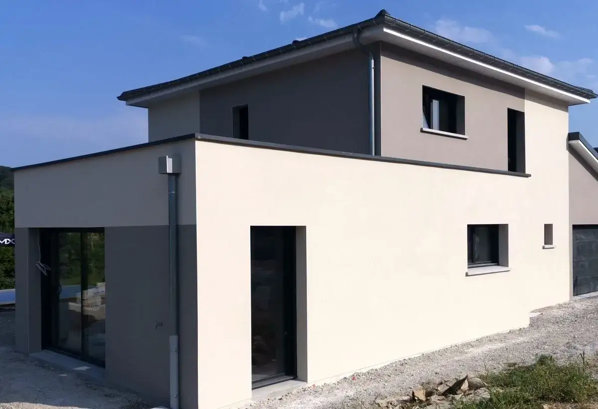 Moderne maison avec façade 2 couleurs, beige clair et gris. Grandes fenêtres et toit plat.