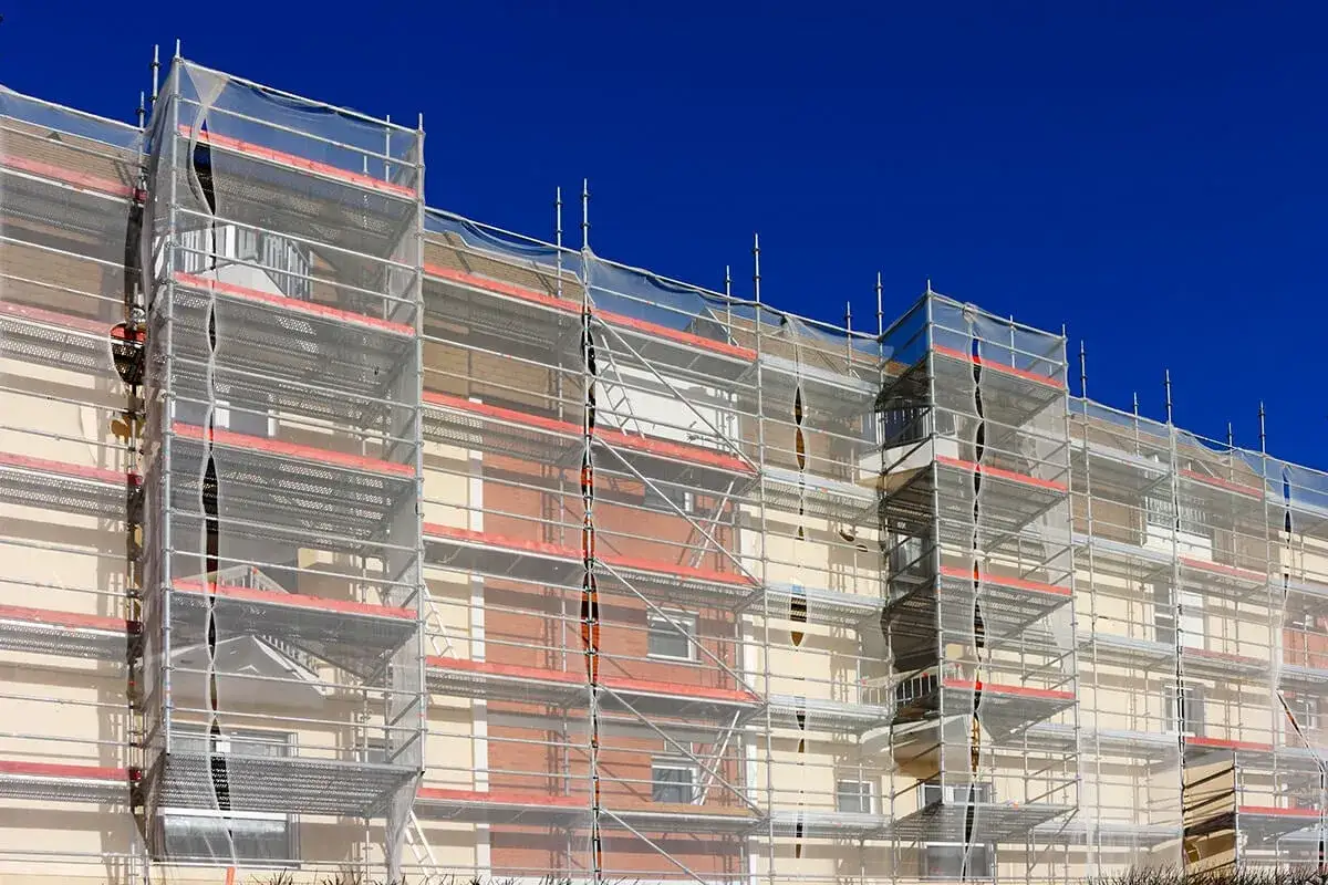 Un immeuble en cours de r&eacute;novation, enti&egrave;rement entour&eacute; d'&eacute;chafaudages et b&acirc;ch&eacute;. La peinture de fa&ccedil;ade sera bient&ocirc;t termin&eacute;e.